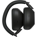 Image of Sony WH-1000XM6 Black standing upright on one earcup with the headband arched above, showcasing minimalist styling.
